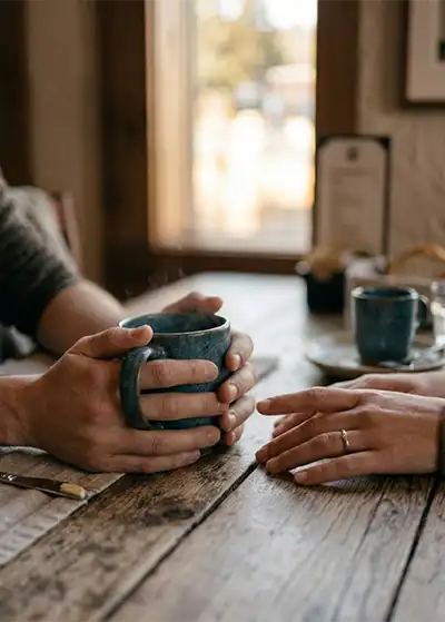 A man and woman's hands on a coffee table